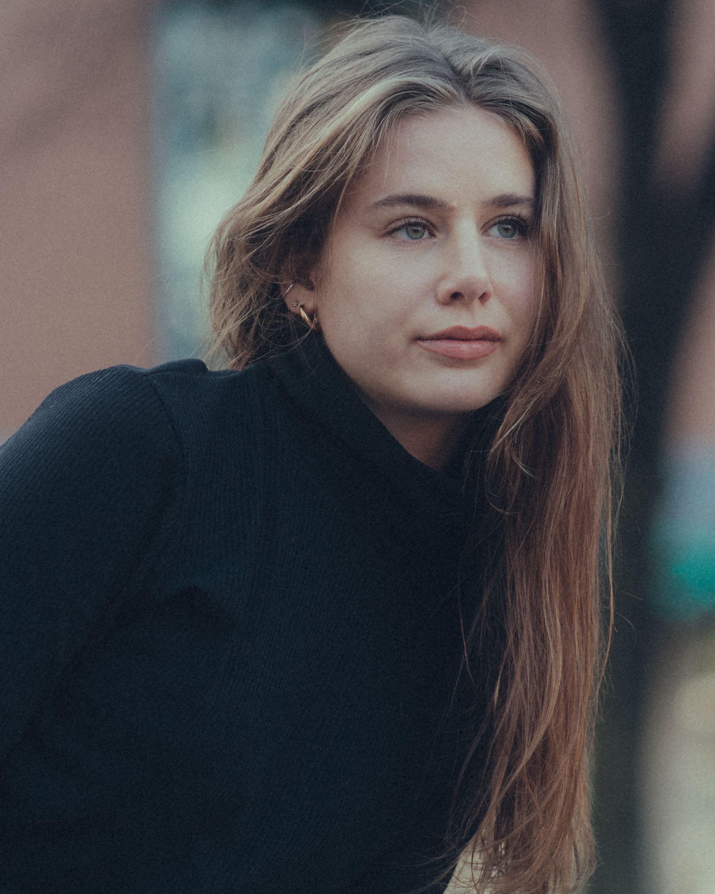 A serene portrait capturing a young woman with blonde hair and a contemplative expression, set against an outdoor backdrop.
