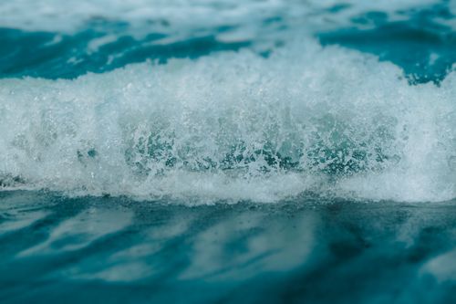 Free A detailed view of an ocean wave breaking with frothy white foam on the surface. Stock Photo