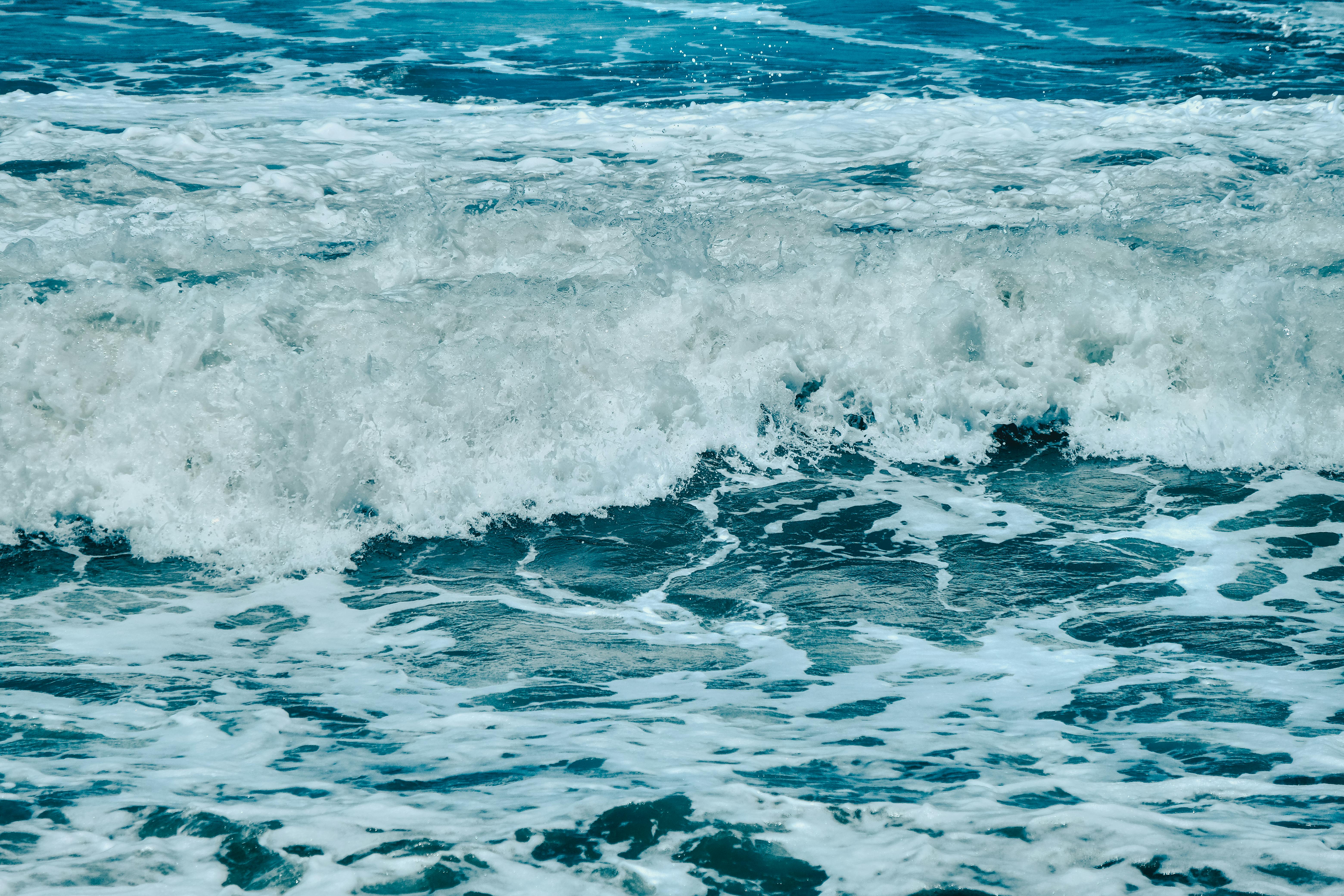 Vibrant capture of ocean waves with foam splashes on a sunny day, showcasing nature's power.