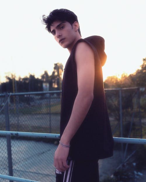 A young man in a hoodie standing on a fence