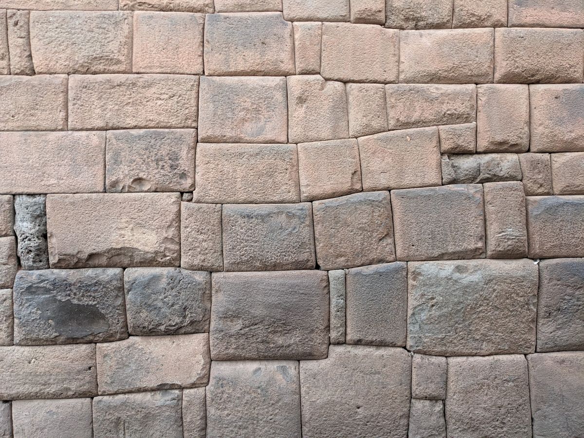 Close-up of precisely fitted polygonal Inca stone masonry in Cusco, irregular multi-sided blocks locked together with no visible mortar.