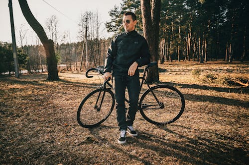 A man standing next to his bike in the woods