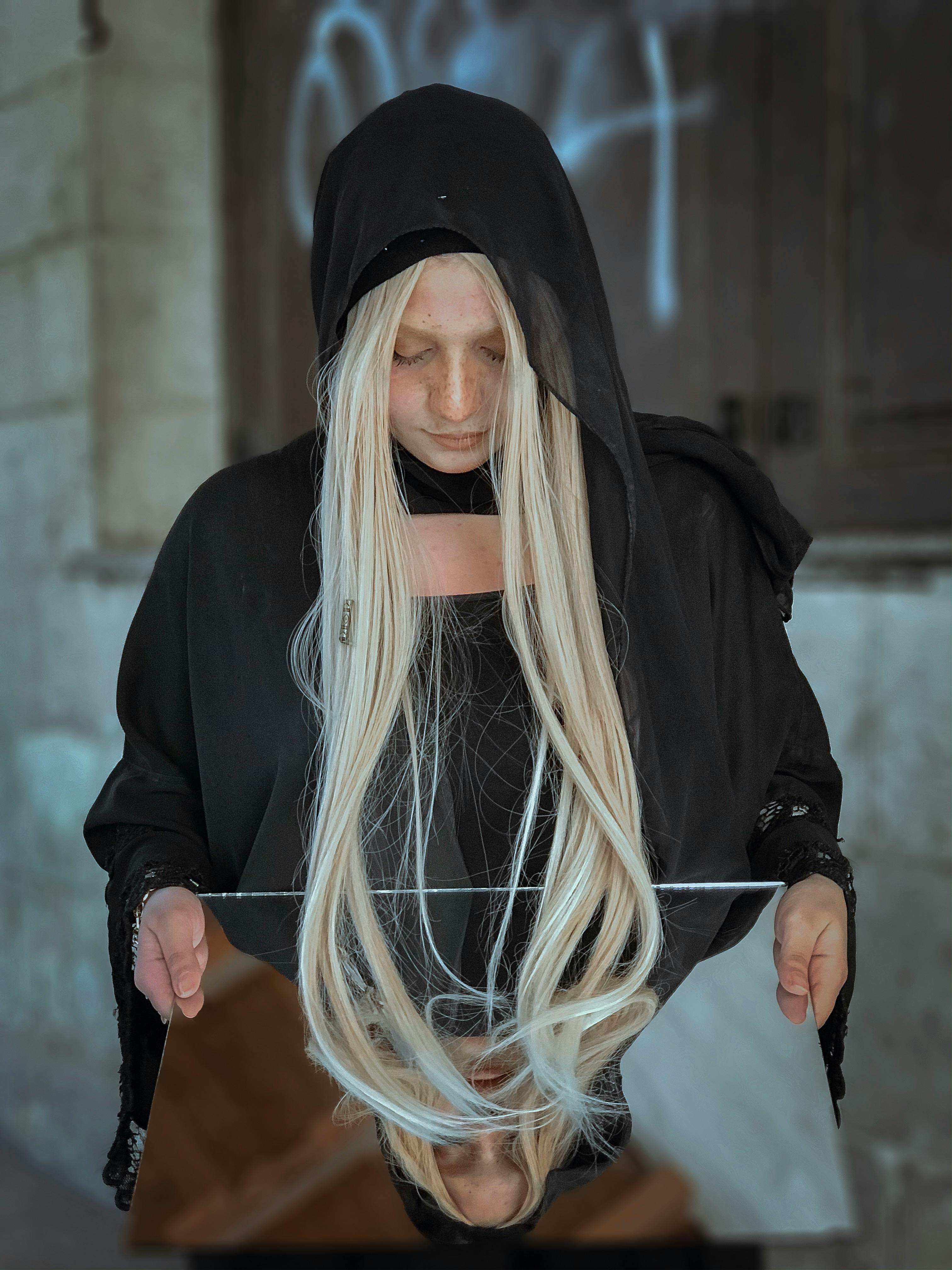 一名身穿黑色连帽衫的女子凝视着反光镜，显得神秘莫测