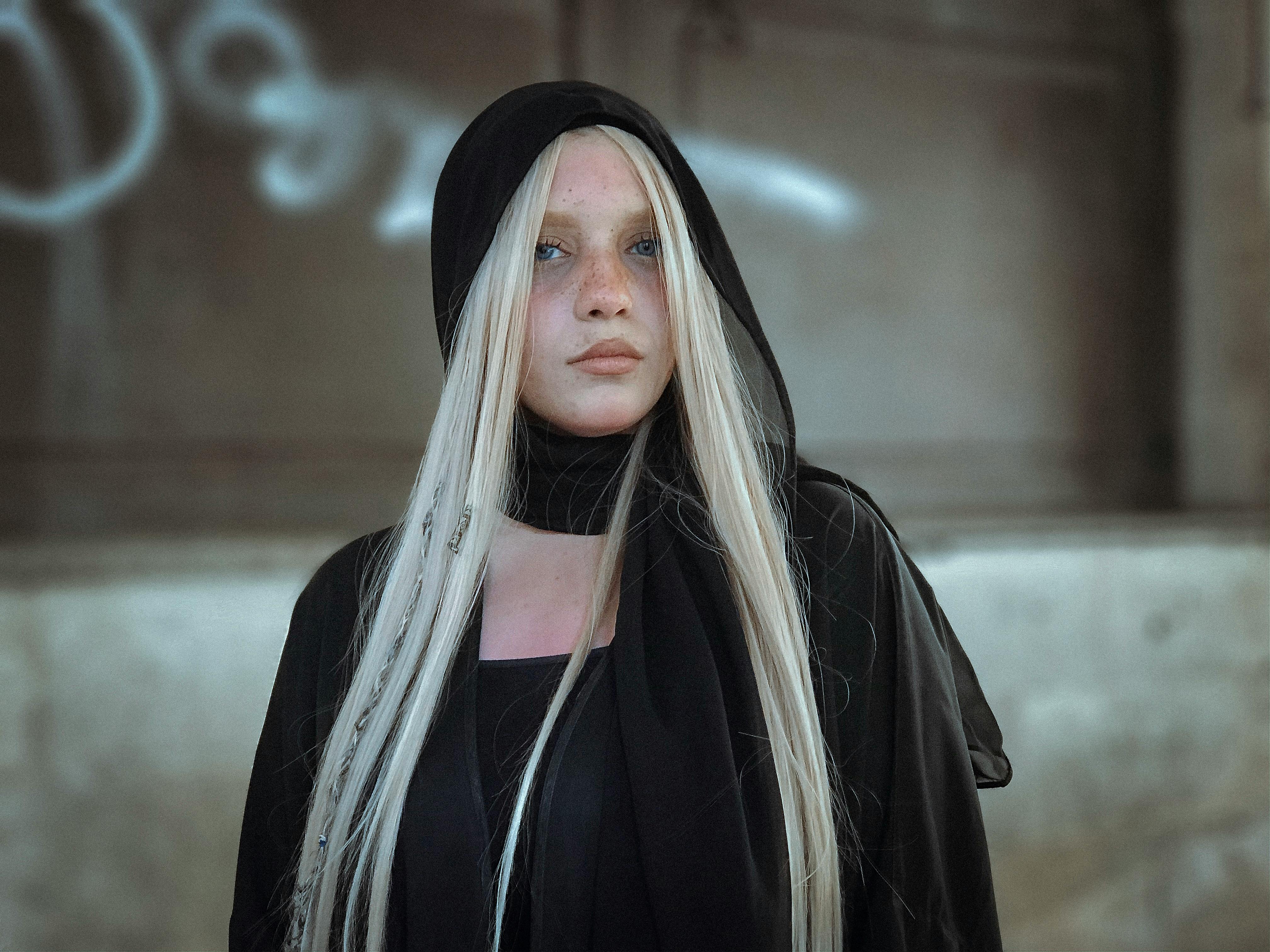 在城市背景下，一位留着金色长发、戴着黑色头巾的女性肖像引人注目