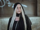 在城市背景下，一位留着金色长发、戴着黑色头巾的女性肖像引人注目