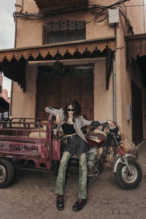 A woman sitting on a motorcycle next to a building