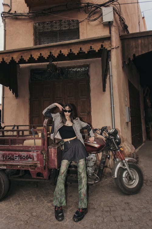 A woman in a green outfit posing next to a motorcycle