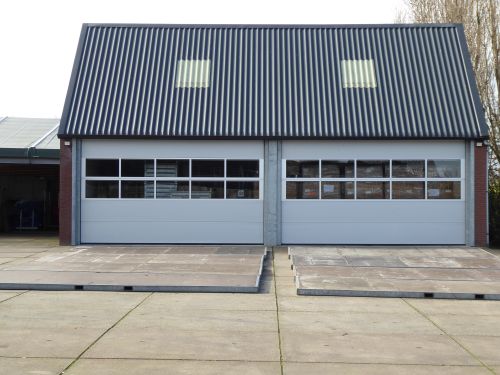 Free Front view of a modern warehouse building with corrugated roofing and skylights. Stock Photo