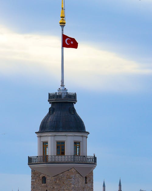 A flag flying on top of a tower with a clock