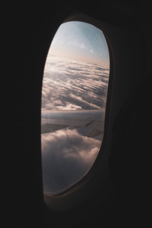 Free View from airplane window of clouds during sunrise. Perfect for travel and aviation themes. Stock Photo
