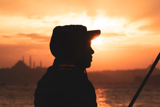 A stunning silhouette of a fisherman against an İstanbul sunset, capturing the city's iconic skyline.
