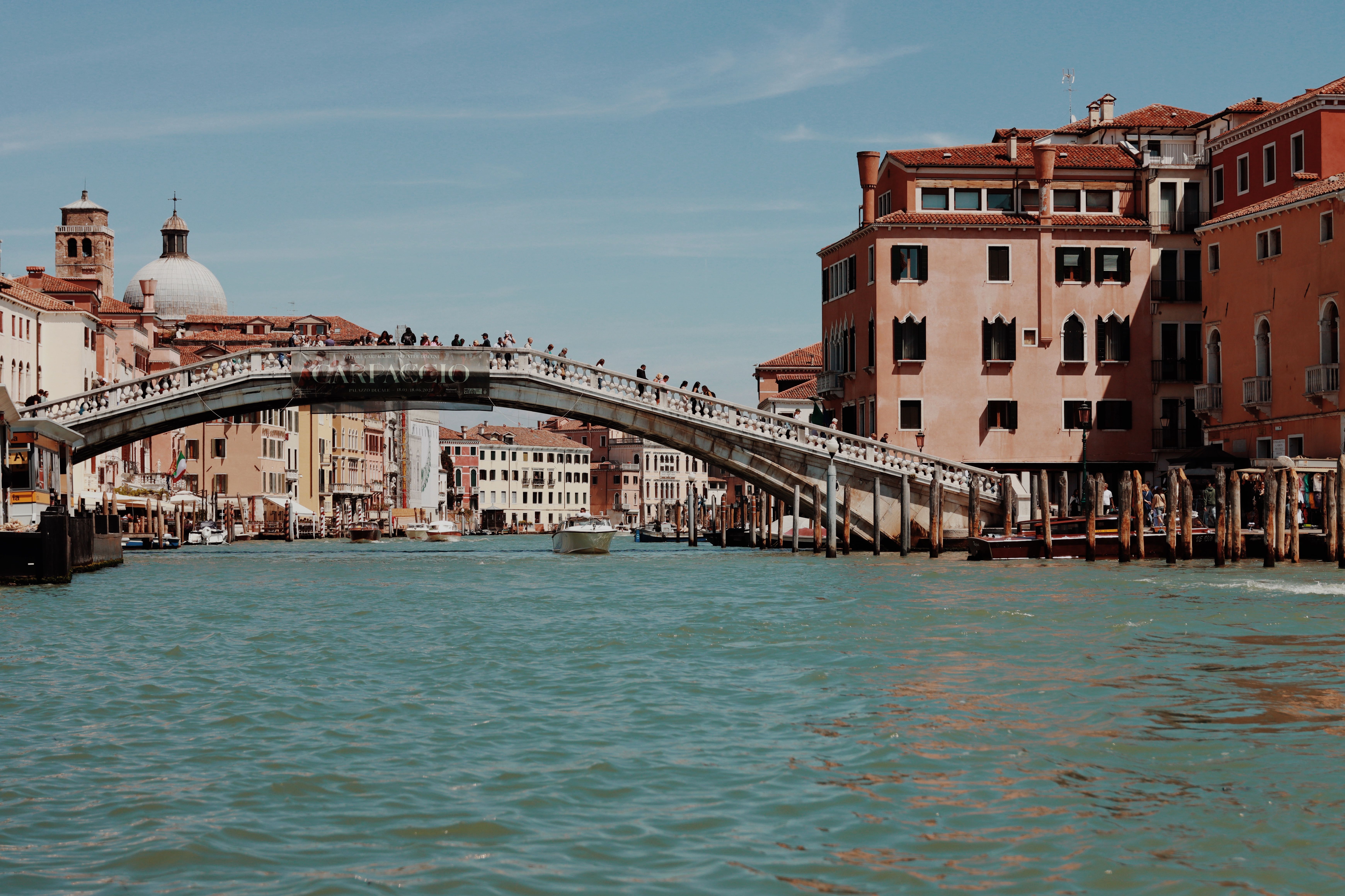 Scenic view of a historic bridge spanning a canal in Venice, Italy, captured on a sunny day.