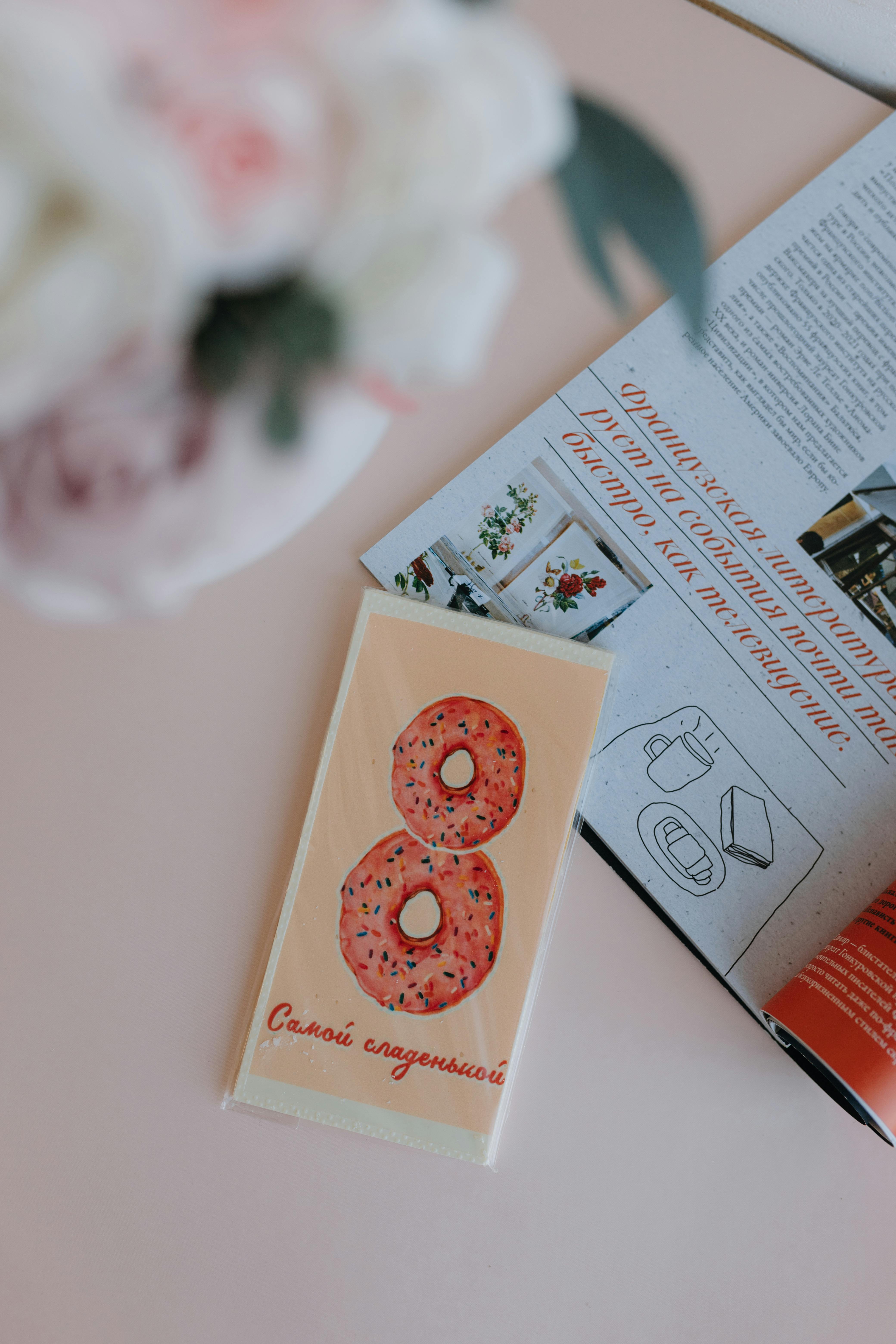 Artistic flat lay featuring a donut illustration and an open magazine on a pastel surface.