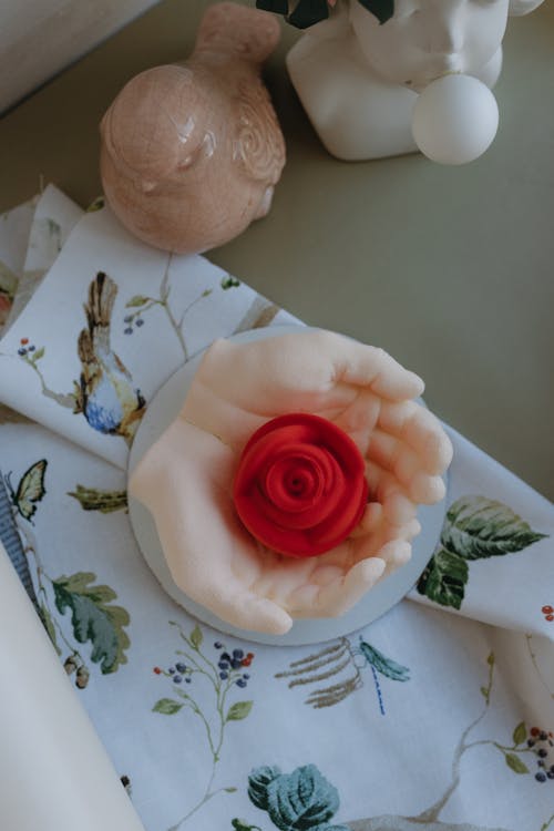 A small rose on a table next to a bird