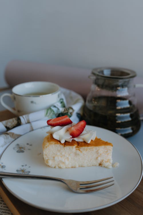 A slice of cake on a plate next to a cup of coffee