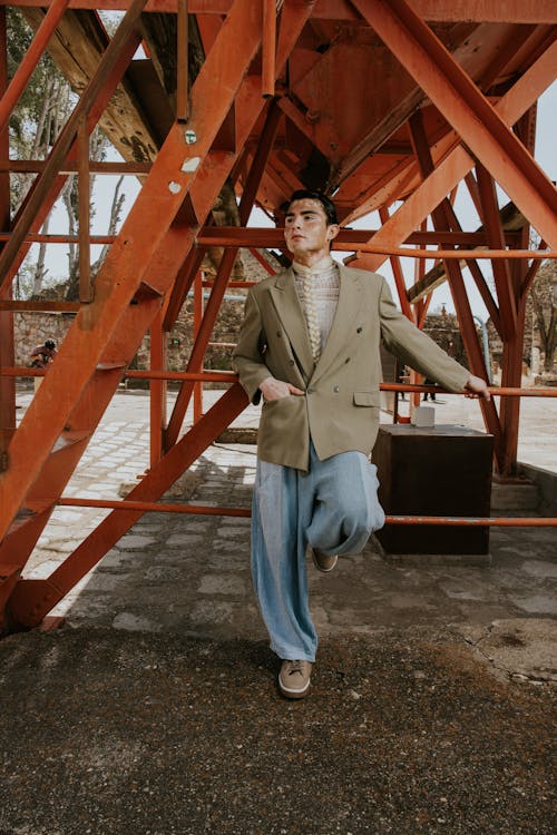 A man in a suit and blue pants standing on a metal structure