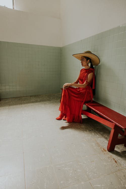 A woman in a red dress sits on a bench