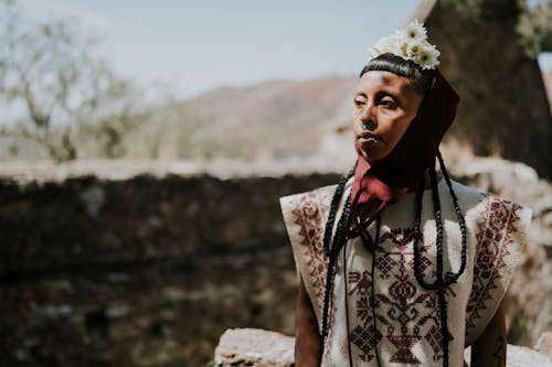 A man in a traditional dress with a flower on his head