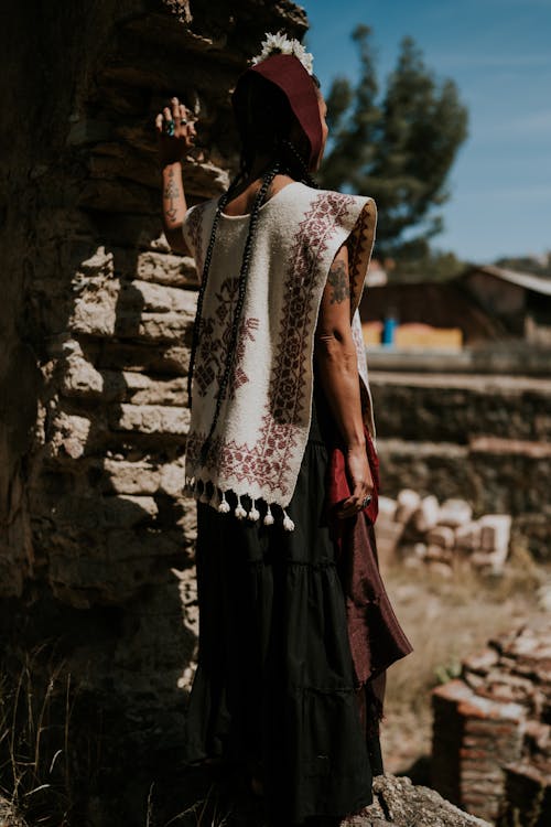 A woman in a skirt and a long top standing on a rock