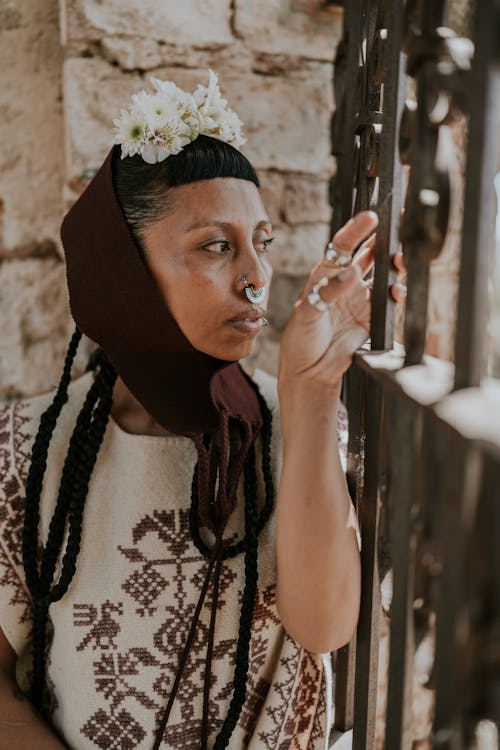 Photo of a Woman with Braided Hair and Nose Piercing Posing in a Patterned Poncho 