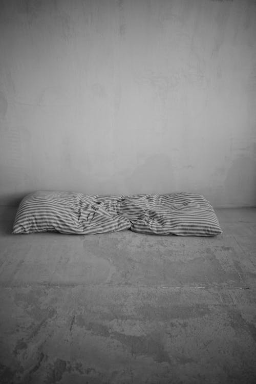 A black and white photo of a pillow on the floor