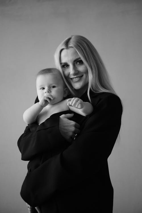 A woman holding a baby in black and white