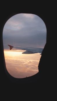 Serene aerial view from an airplane window during sunset, capturing a tranquil sky and distant horizon.