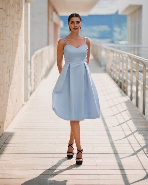 A woman in a light blue dress is walking on a boardwalk