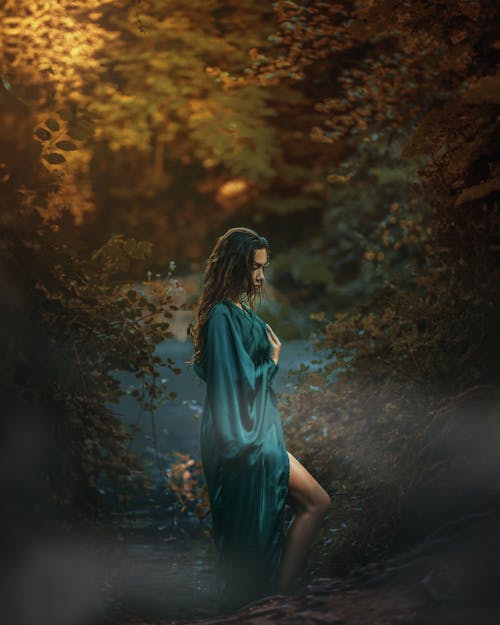 A woman in a green dress standing in the woods