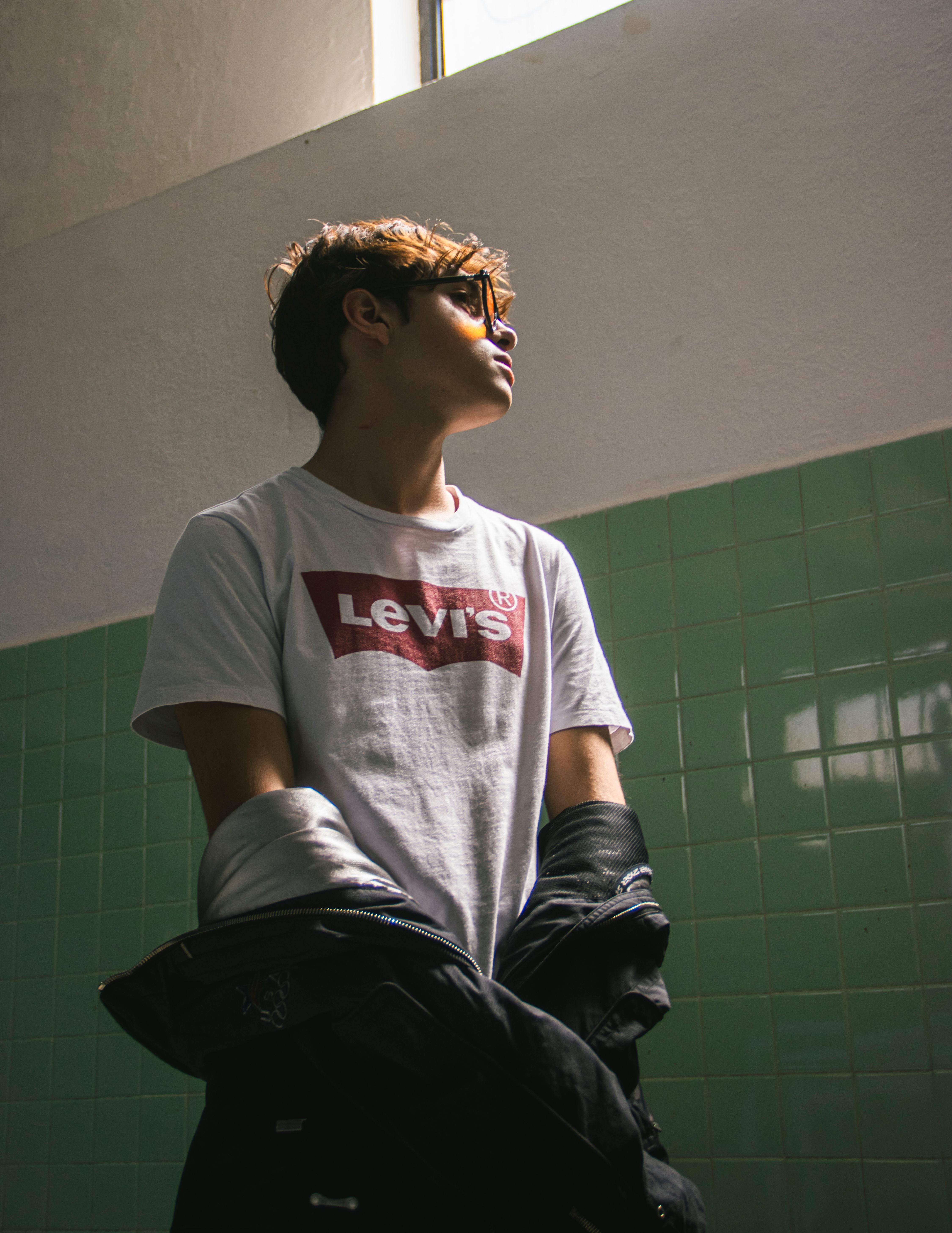 Stylish teenager in sunglasses standing indoors with urban vibes.