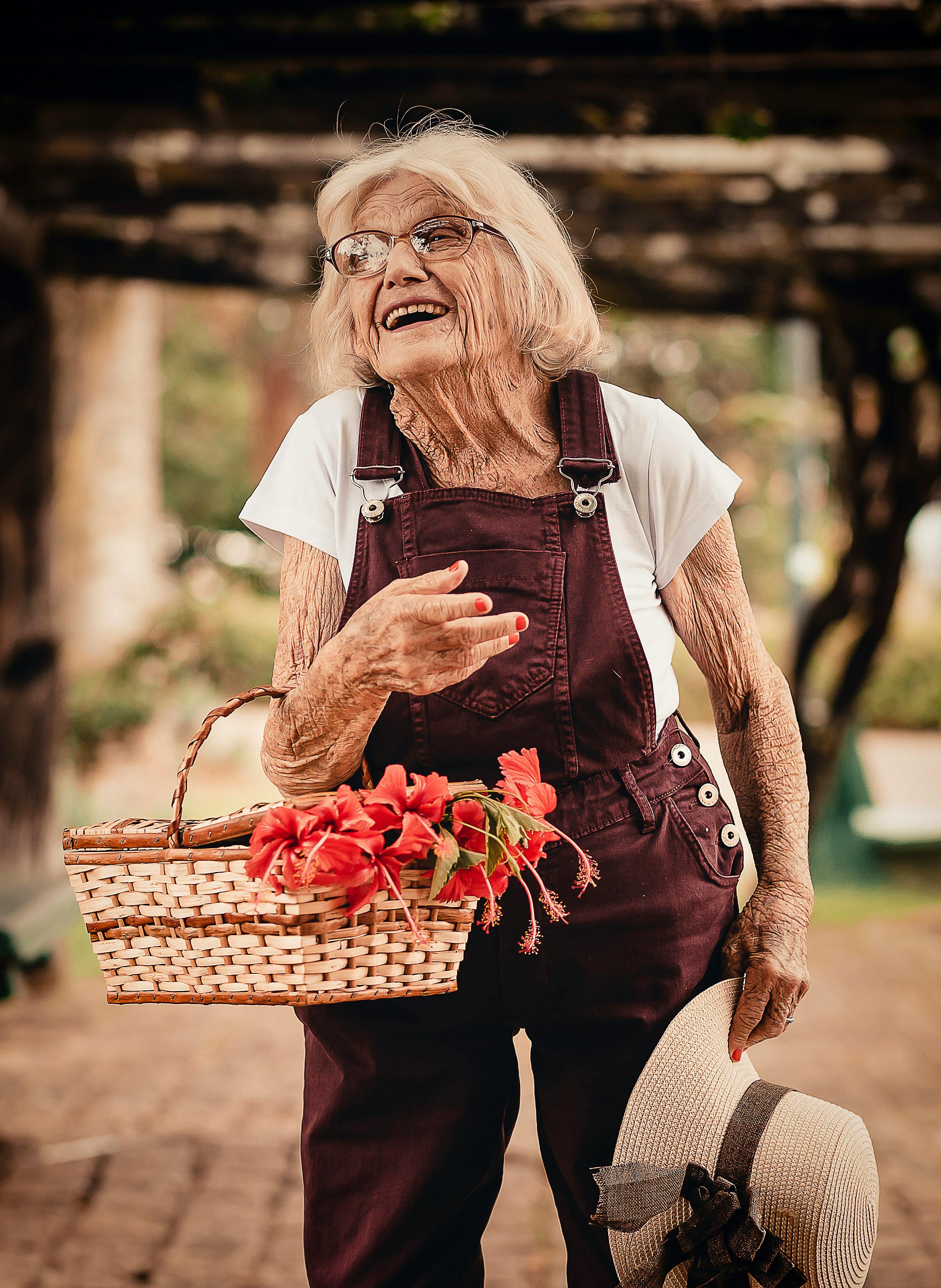 Old woman holding sunhat and picnic basket | Photo: Pexels