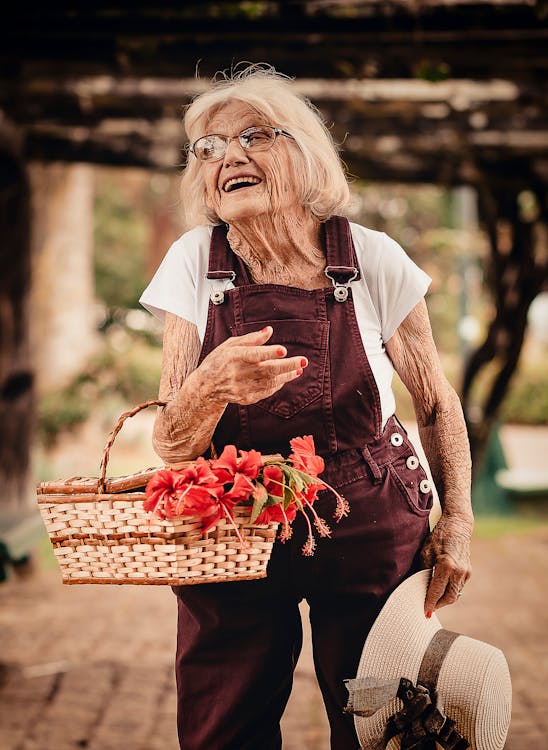 Woman Wearing Brown Dungaree Pants Holding Sunhat and Picnic Basket