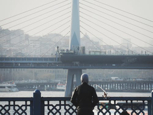 A man is standing on a bridge looking at the water