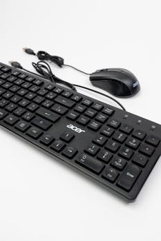 Modern black keyboard and mouse set with wired connections on a white surface.