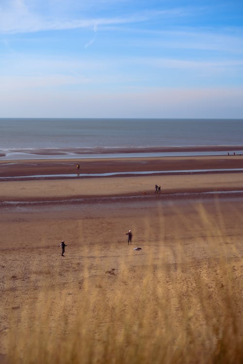 A group of people walking on a beach with a blue sky