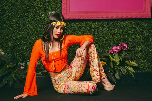 A woman in orange pants and a flower headband posing