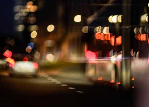 An abstract view of defocused city lights at night creating a vibrant bokeh effect along the street.