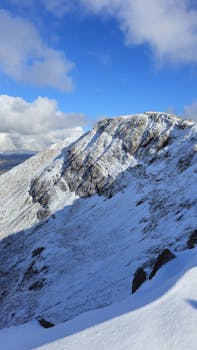 Stunning view of a snow-capped mountain peak in Wales, UK, under a clear blue sky.
