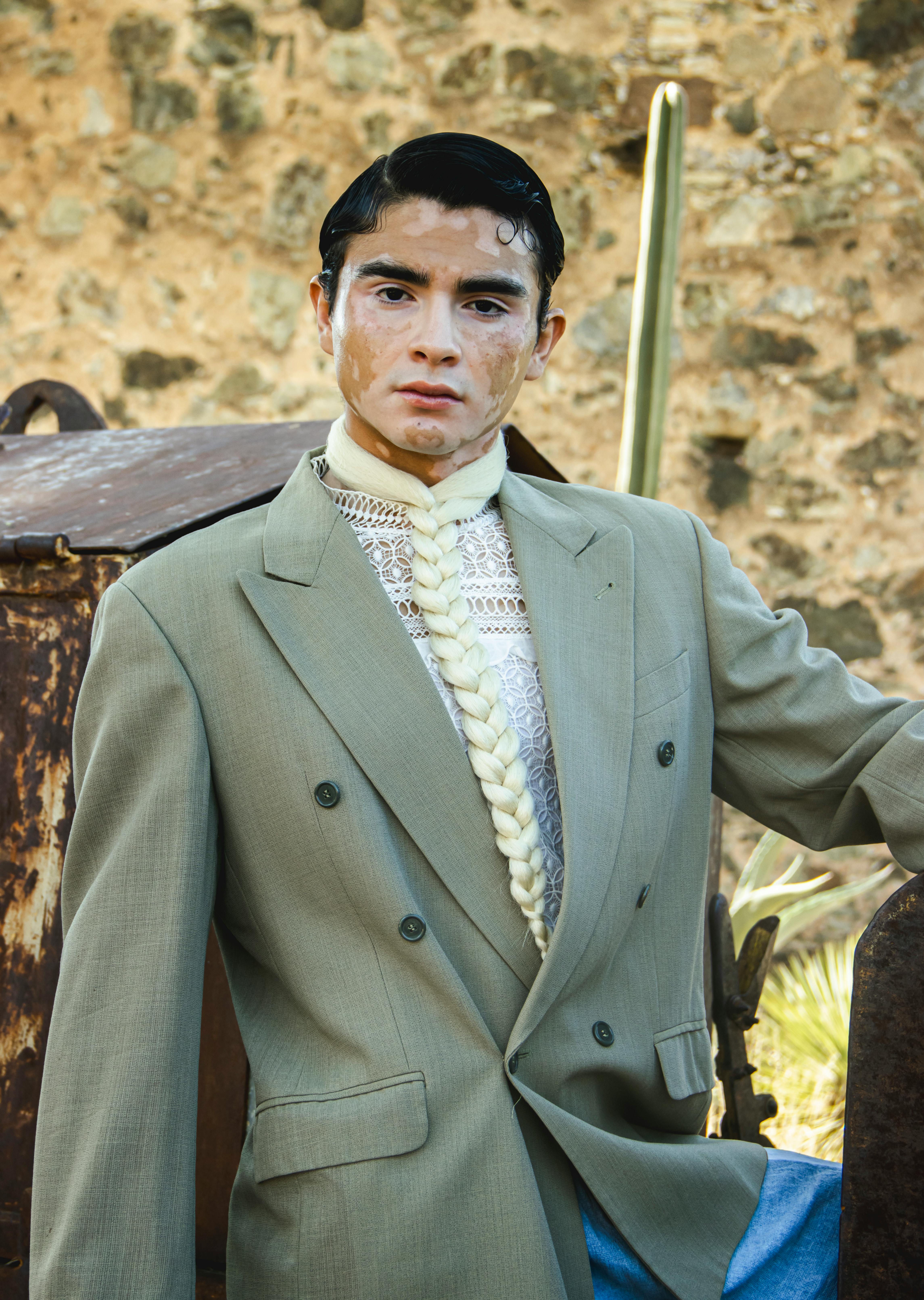 Model with unique style, olive blazer and braided tie posing outdoors.