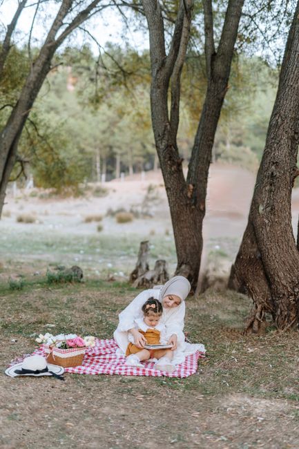 A mother and daughter enjoying a picnic on a forest floor, surrounded by trees.