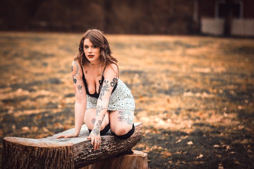 Attractive Tattooed Woman in Black Top and Skirt Posing on Wooden Bench