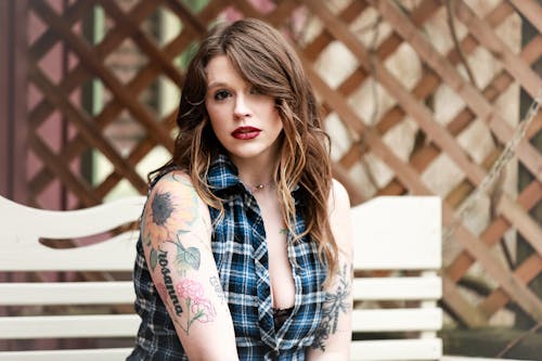 A woman with tattoos sitting on a bench
