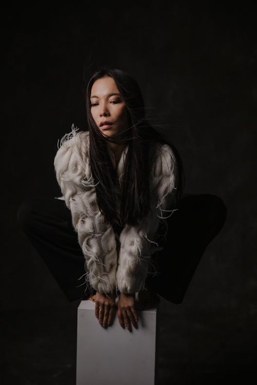 A woman sitting on a white box with her legs crossed