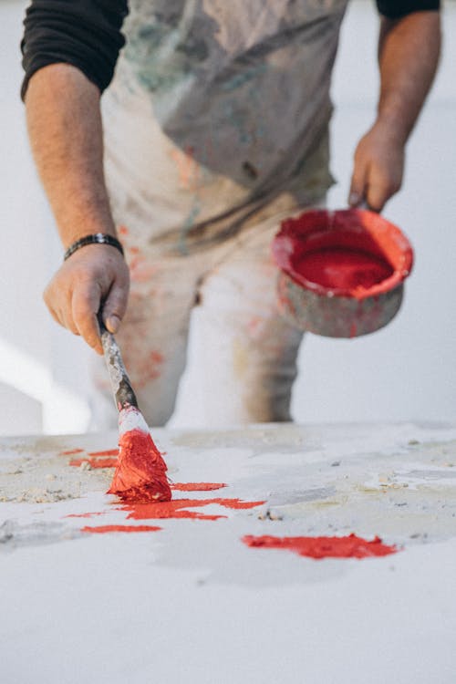A man painting red paint on a table