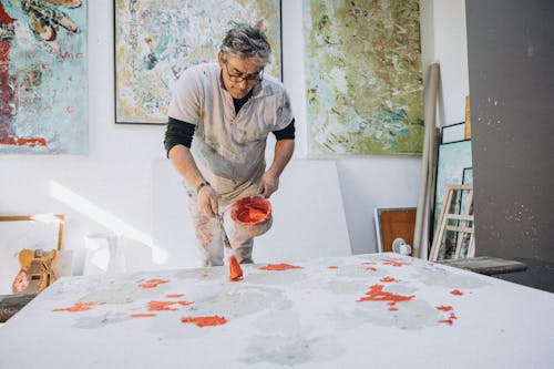 A man painting on a large canvas in an art studio