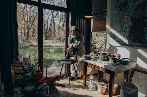 A man in a suit is standing in front of a window