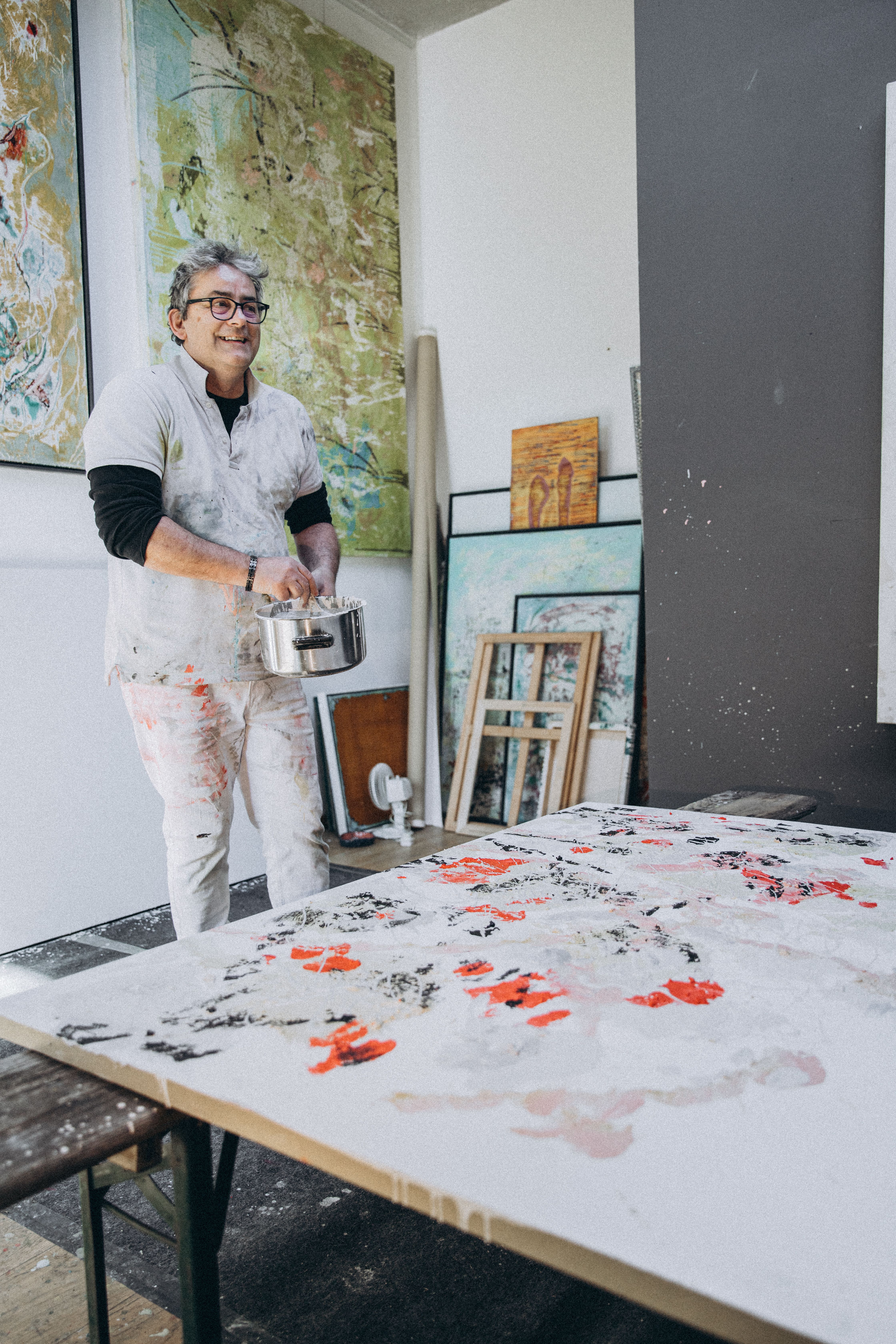 Smiling artist in studio painting canvas with vibrant colors.