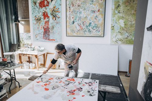 Free A male artist painting on a canvas in a modern studio with abstract art pieces. Stock Photo