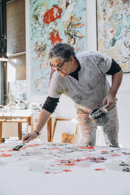 A man painting on a large canvas in an art studio