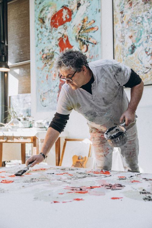 Free An artist intently works on an abstract painting in a bright studio setting. Stock Photo